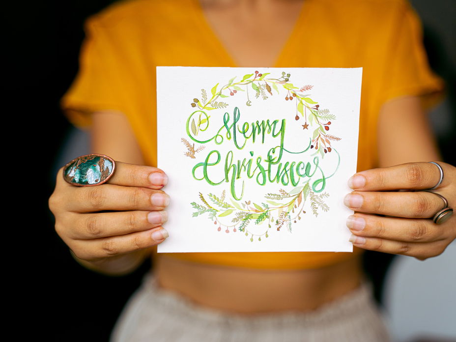 Frau hält eine Weihnachtskarte mit Weihnachtswünschen in der Hand