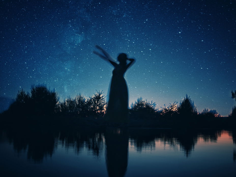 Schattenbild einer Frau an einem See in der Nacht