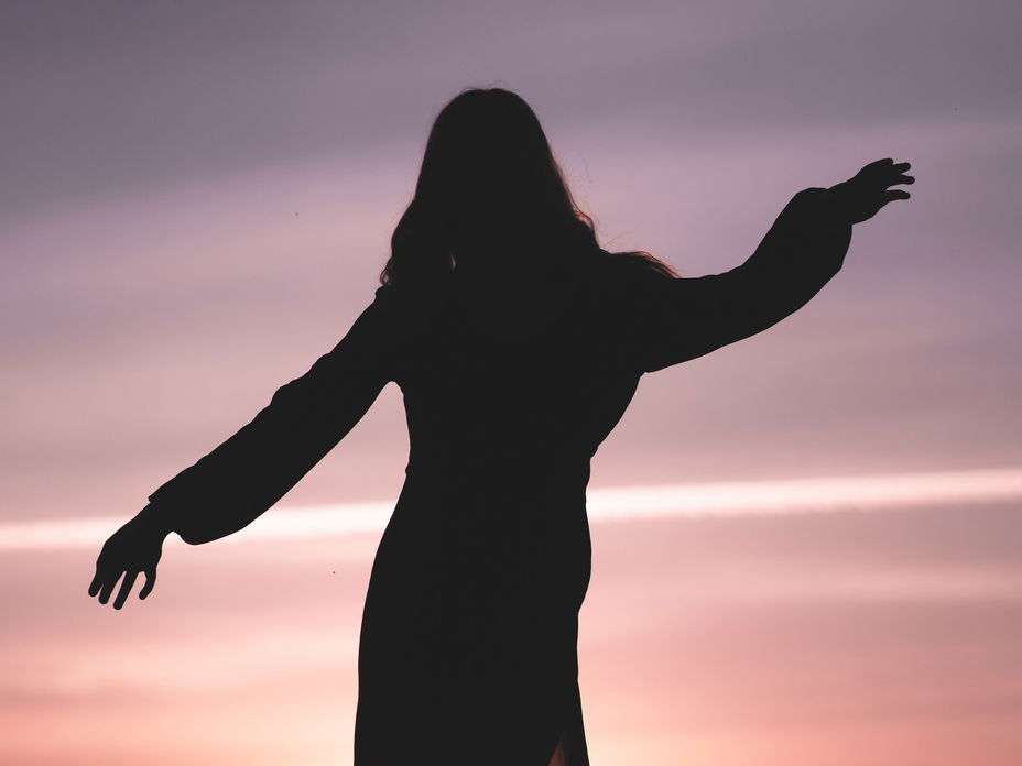 Silhouette einer Frau im Kleid während eines Sonnenuntergangs