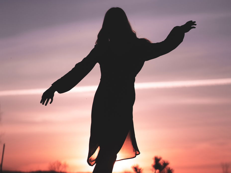 Silhouette einer Frau im Kleid während eines Sonnenuntergangs