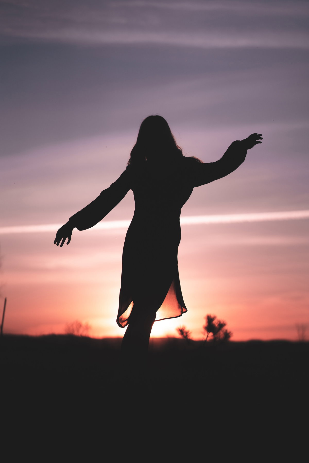 Silhouette einer Frau im Kleid während eines Sonnenuntergangs