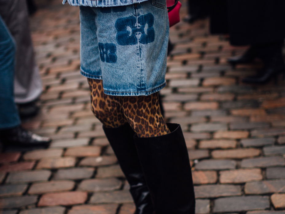 Frau trägt auf Copenhagen Fashion Week Jeans Kombi und Leomuster Strumpfhose und spitze schwarze Stiefel