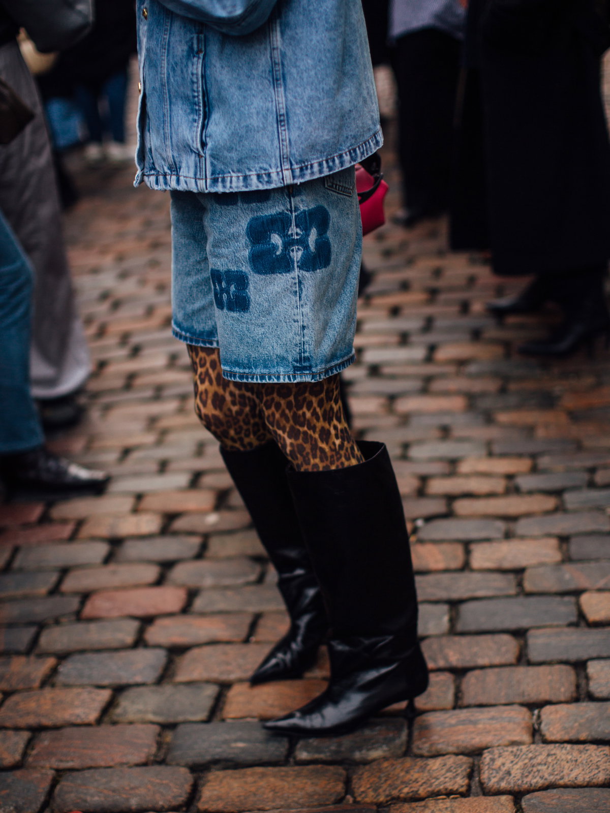 Frau trägt auf Copenhagen Fashion Week Jeans Kombi und Leomuster Strumpfhose und spitze schwarze Stiefel