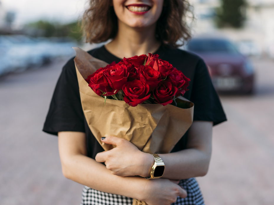 Frau hält einen Strauß mit roten Rosen in der Hand