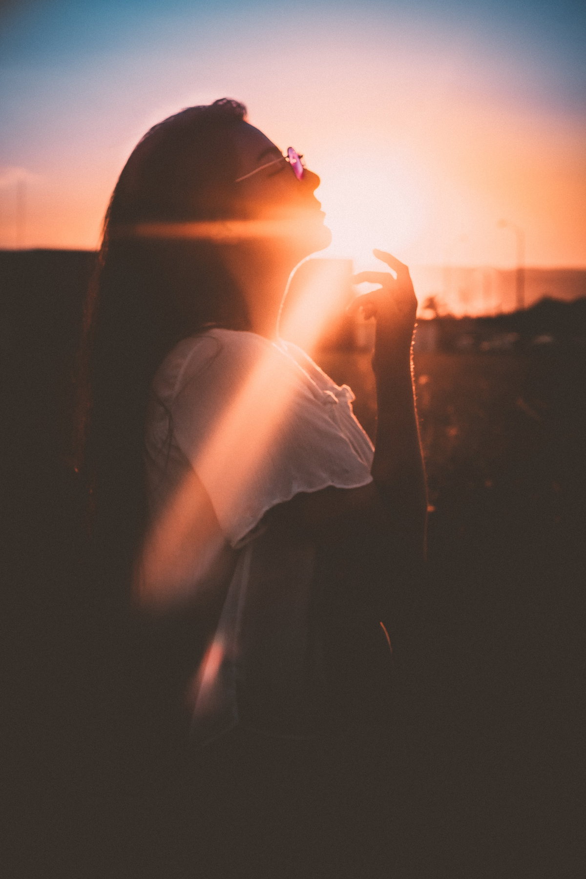 Frau mit langen Haaren und Brille beim Sonnenuntergang