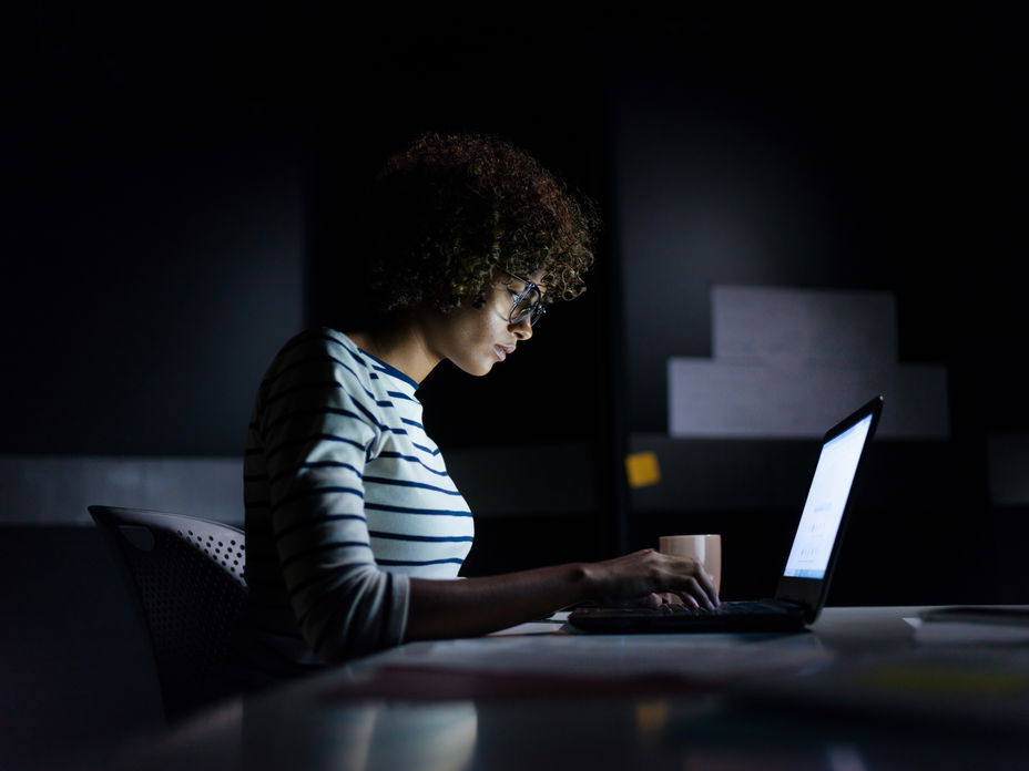 Junge Frau sitzt nachts am Laptop