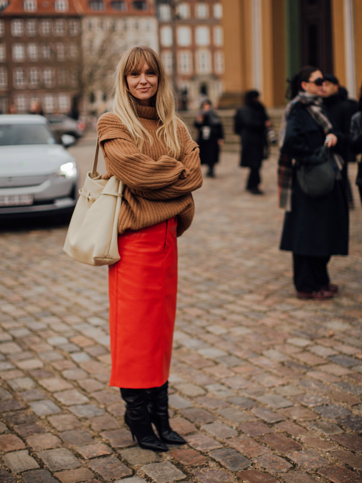 Frau trägt auf Kopenhagen Fashion Week roten Rock in Midi-Länge und kniehohe Stiefel