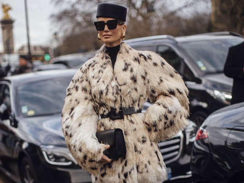Frau trägt auf Paris Fashion Week Fake Fur Mantel XXL Hut und Sonnenbrille plus beigefarbene Overknees
