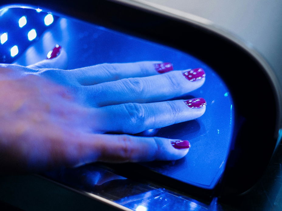 Weibliche Hand mit Nagellack unter UV-Lampe