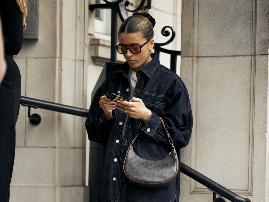 Frau mit Retro-Sonnenbrille schaut auf ihr Handy