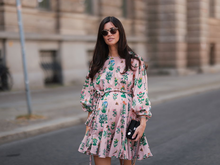 Schwangere Frau im rosanen Kleid mit Sonnenbrille