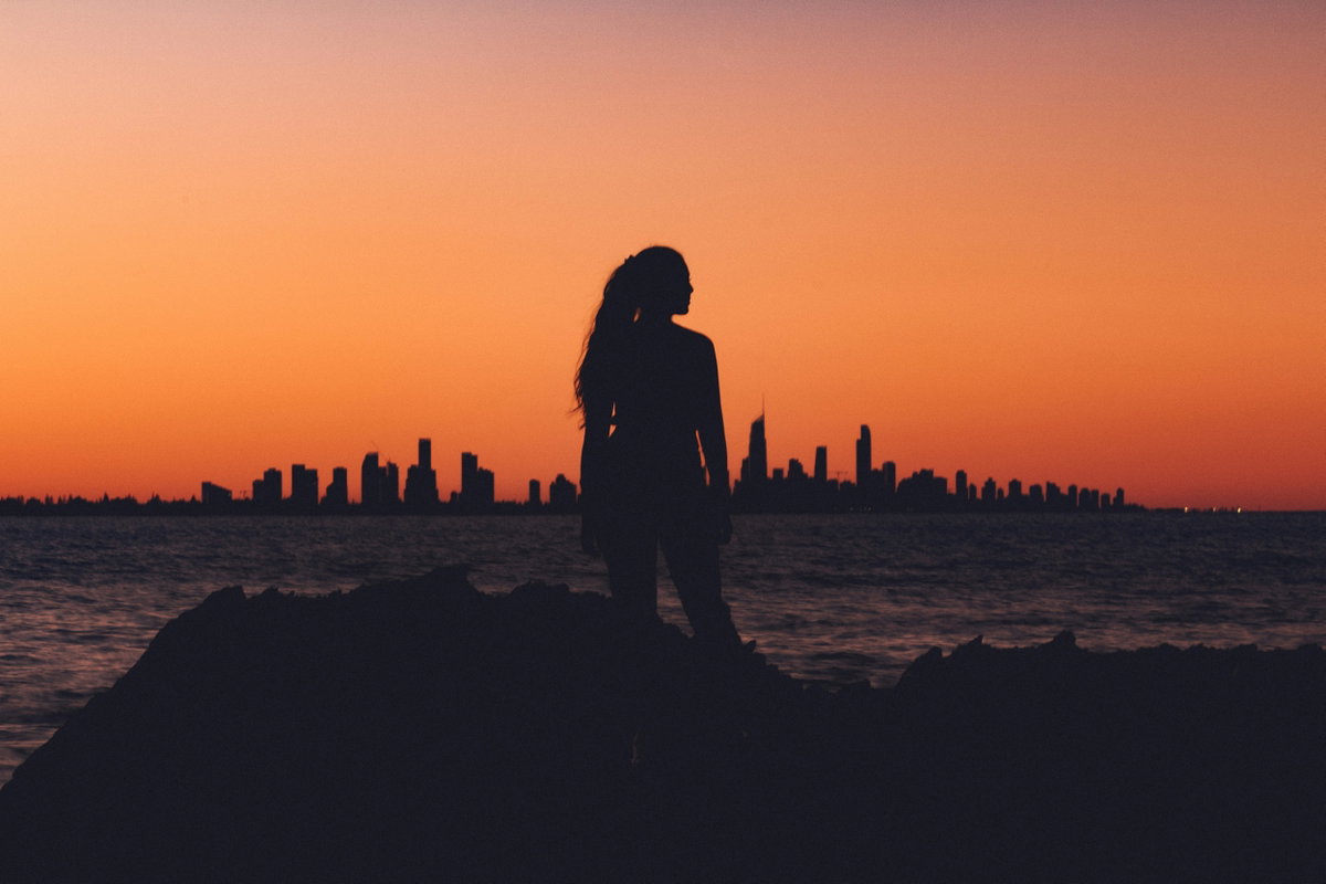 Frau steht vor einer Skyline während des Sonnenuntergangs