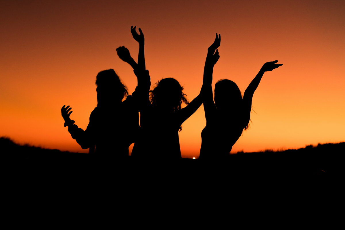 Drei Silhouetten von Frauen vor Sonnenuntergang