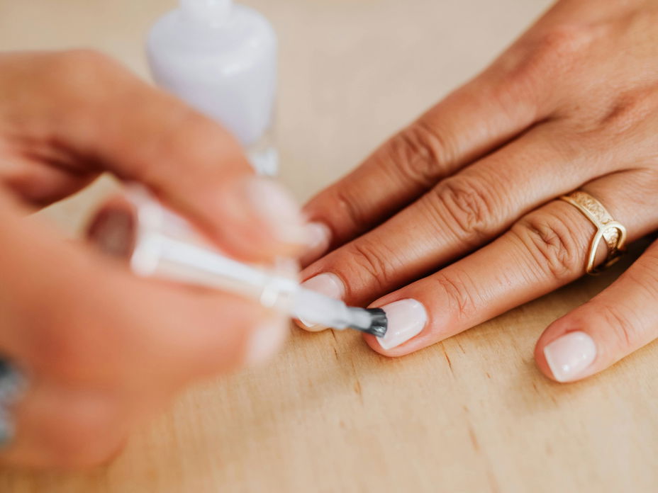 Frau trägt weißen Nagellack auf