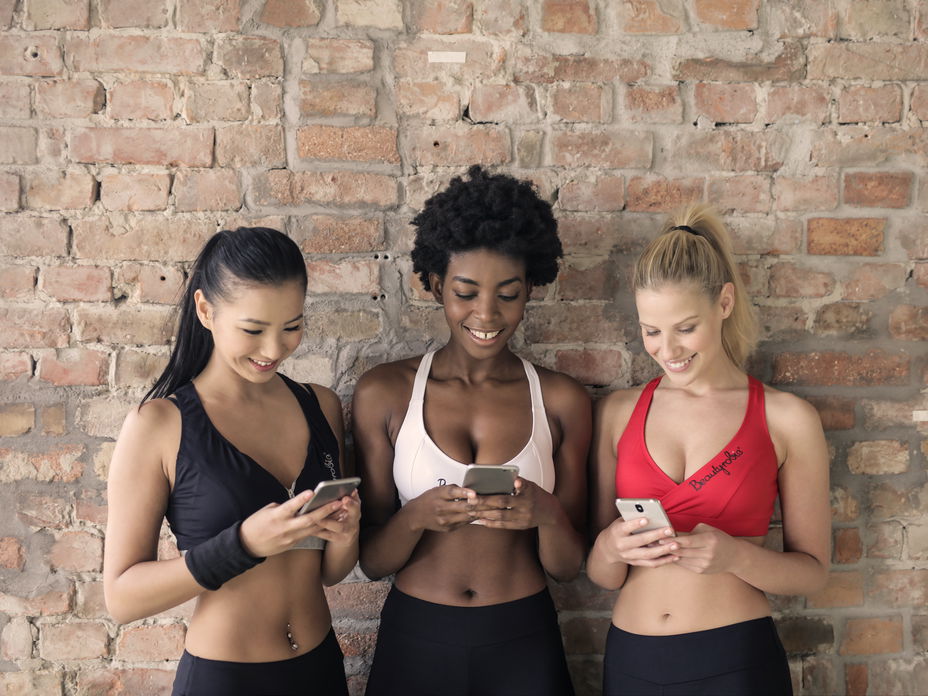 Drei junge Frauen schreiben auf ihren Smartphones