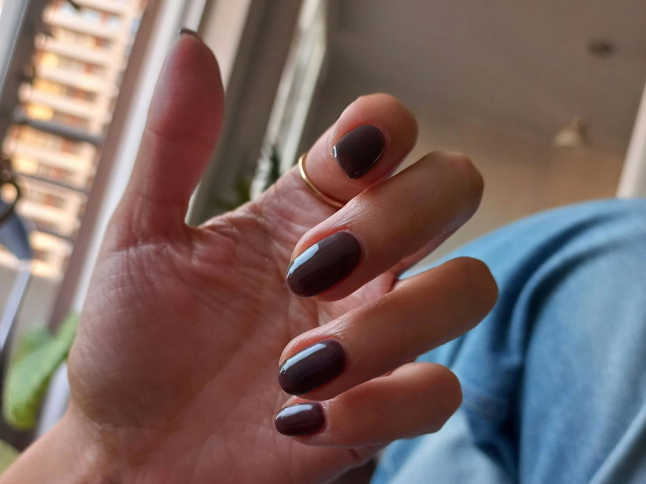 Nägel mit dunkelbrauner Farbe lackiert
