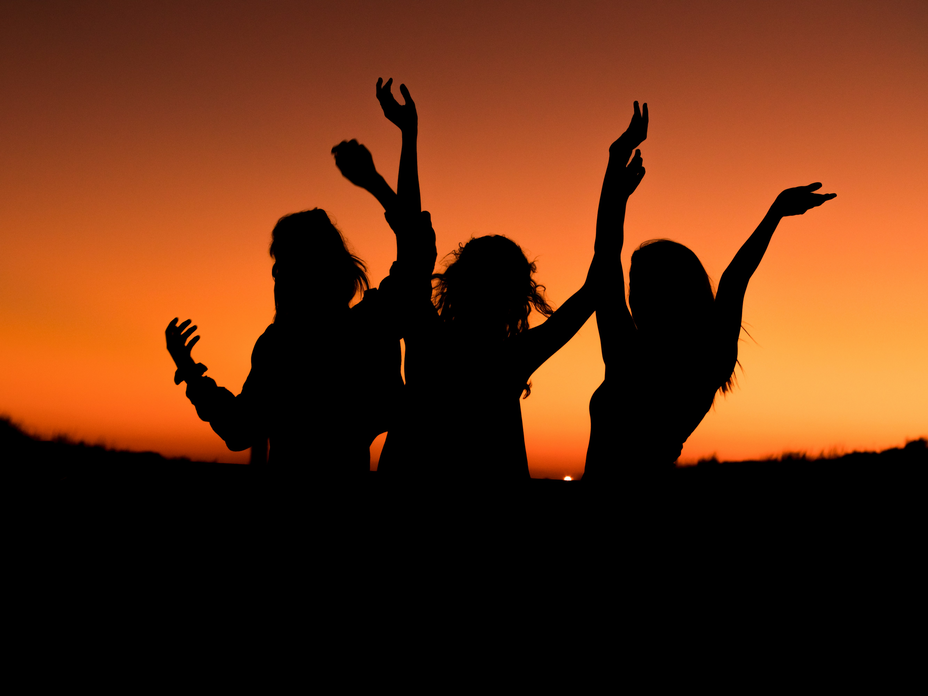 Drei Frauen tanzen unter dem Abendhimmel