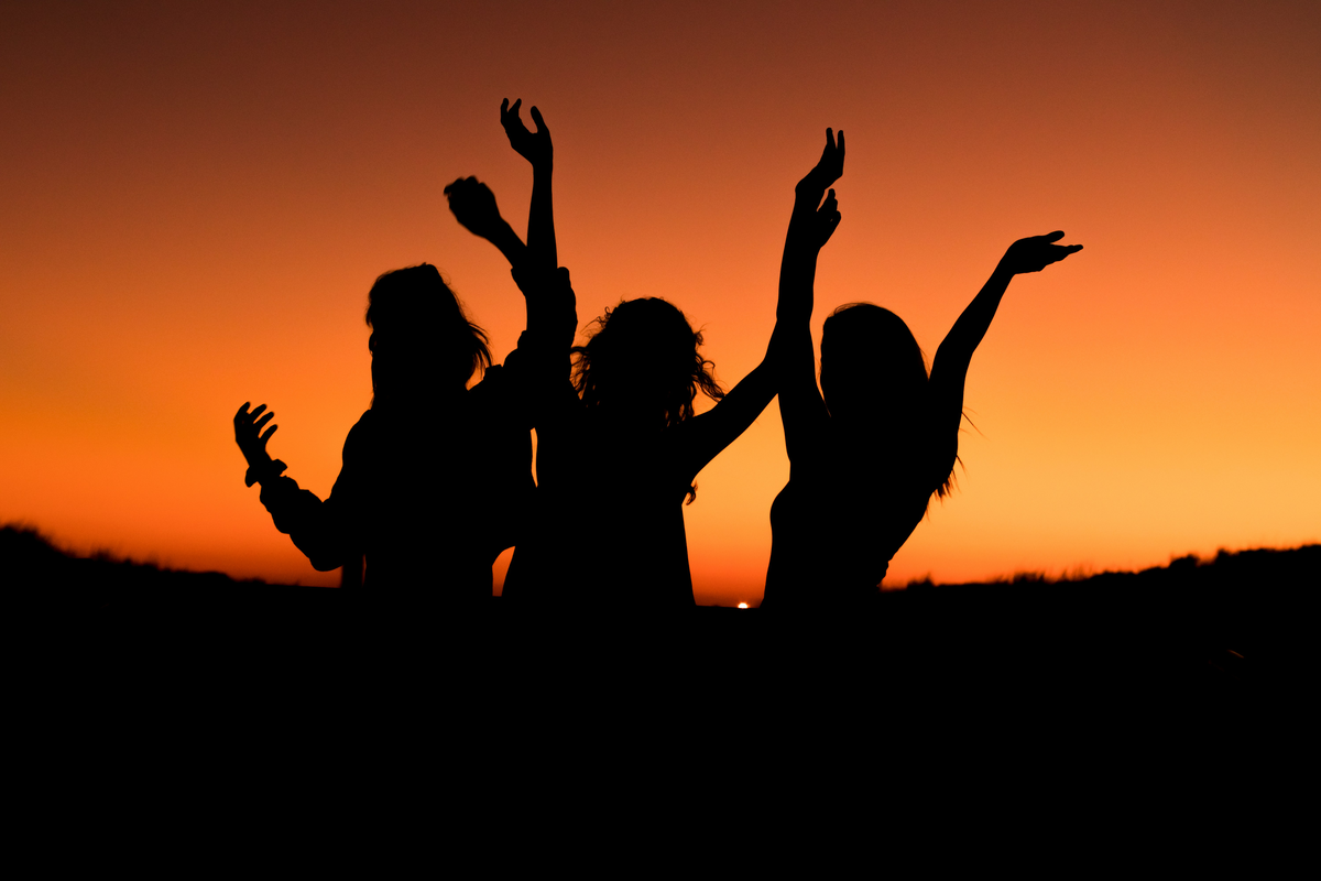 Drei Frauen tanzen unter dem Abendhimmel