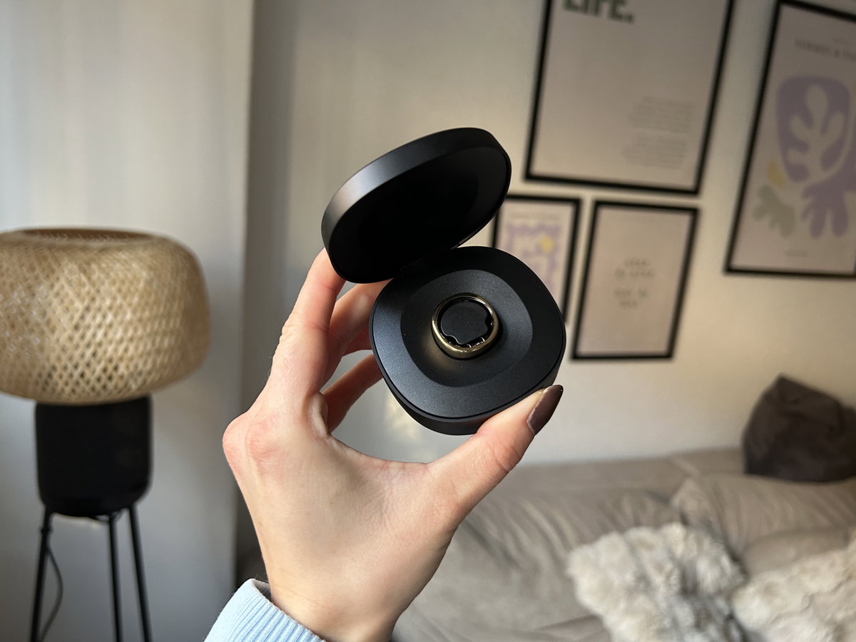 Ein goldener Ring in einer schwarzen Ladebox wird in der Hand gehalten.