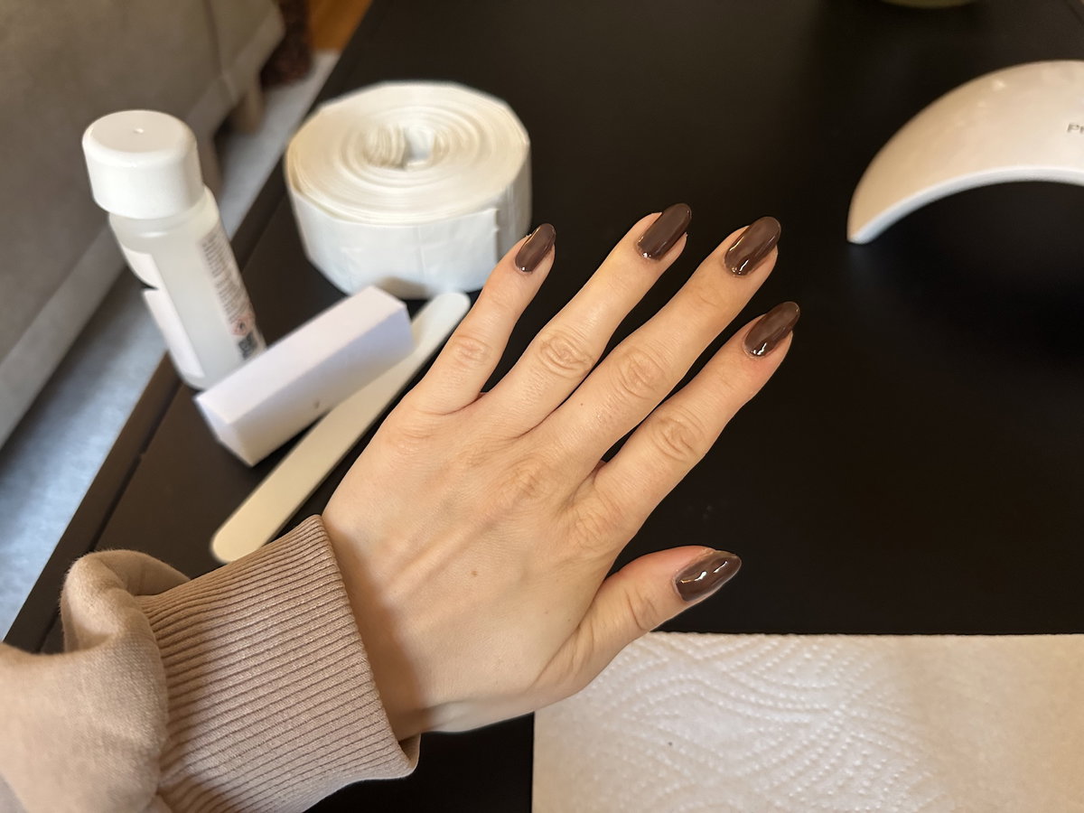 Brauner Nagellack auf den Fingernägeln mit zwei Schichten.