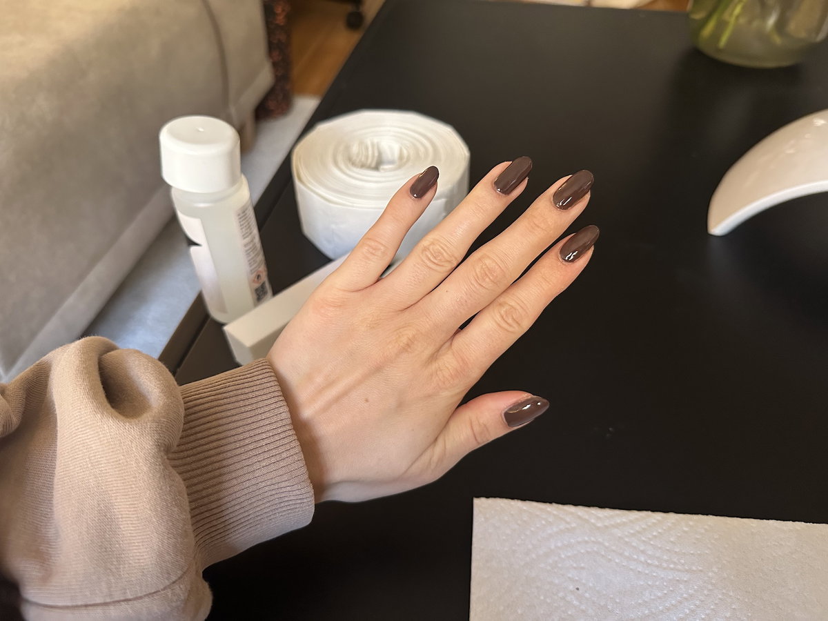 Brauner Nagellack auf den Fingernägeln mit drei Schichten.