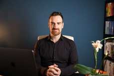 Ramón Schlemmbach auf einem Stuhl vor einer blauen Wand