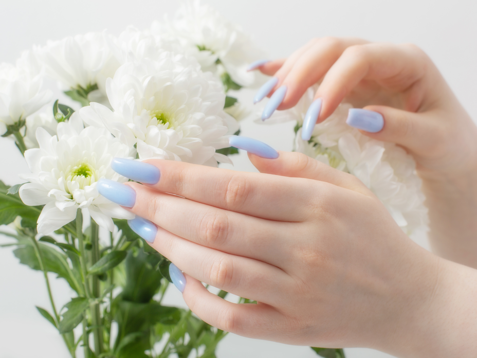 Hände mit hellblauen Nägeln und weiße Blumen