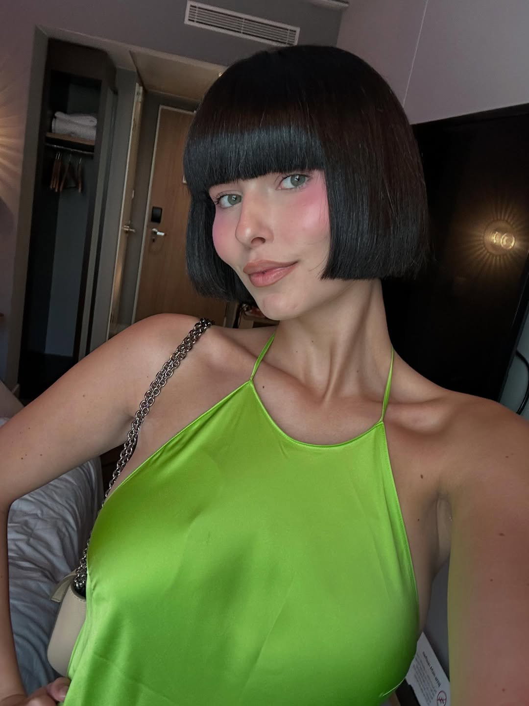 Eine junge Frau mit kurzen, dunklen Haaren und Pony und einem grünen Trägertop.