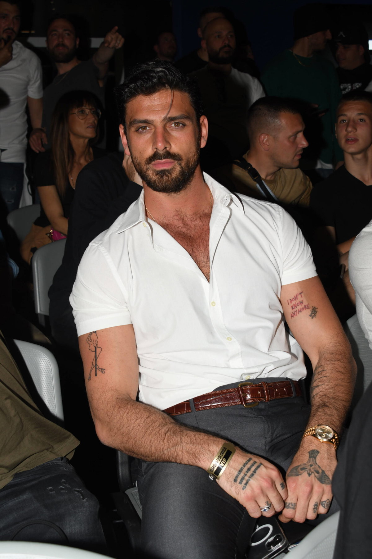 Michele Morrone mit einem weißen, kurzärmligen Hemd und einigen Tattoos an den Armen.