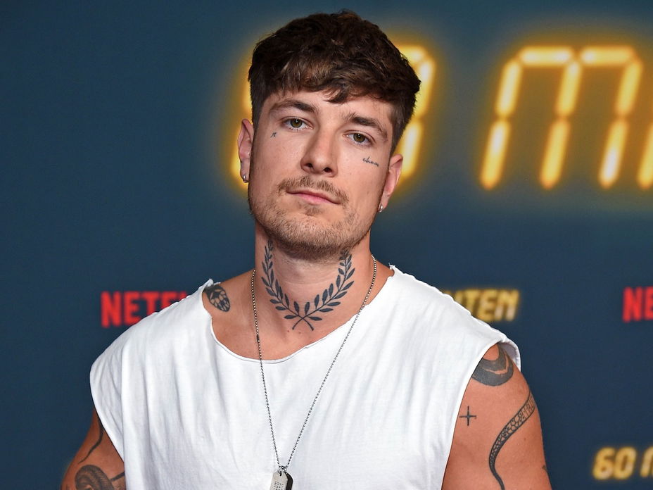 Willi Banner mit einem weißen Tanktop, einer Kette und voll tattoowierten Armen.