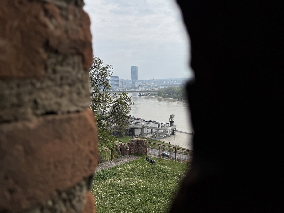 Ein Blick durch einen Mauerspalt auf einen Fluss und die Waterfront in Belgrad.
