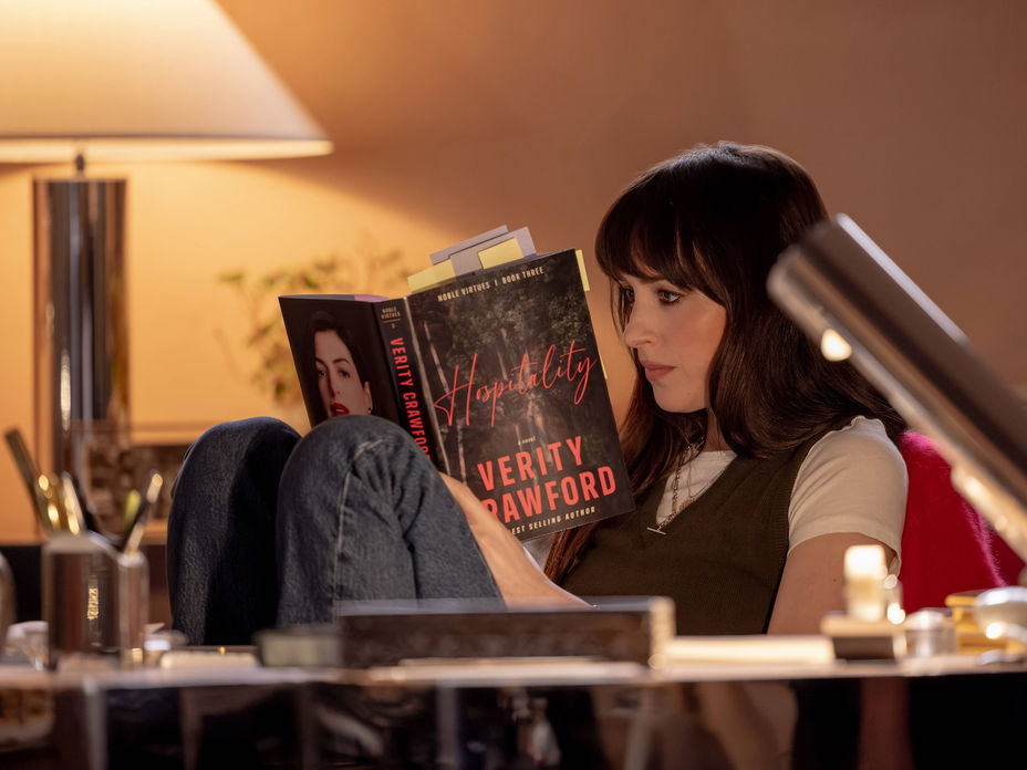 Dakotha Johnson sitzt in einem Zimmer mit gedämmtem Licht und liest ein Buch.