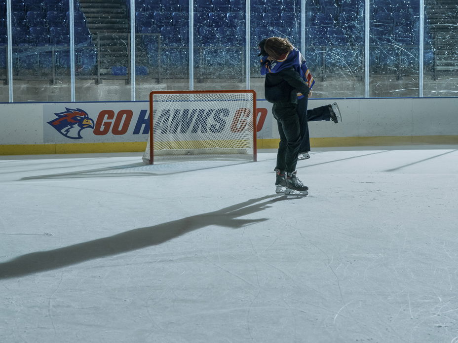 Ein Mann und eine Frau fallen sich auf einem Eishockeyfeld in die Arme.