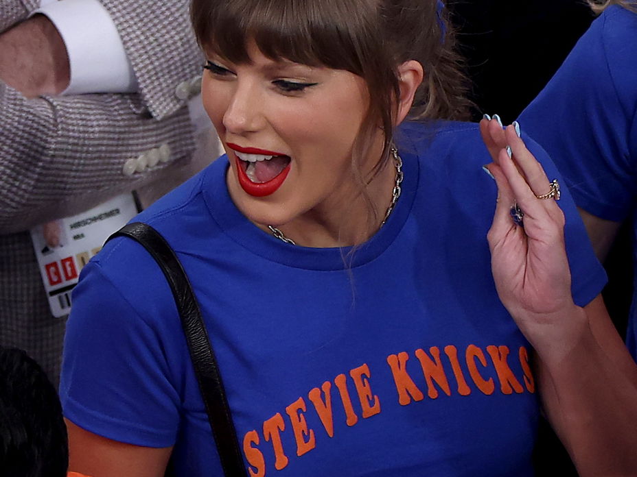 Taylor Swift mit einem blauen Shirt schreit euphorisch und schaut zur Seite nach links.