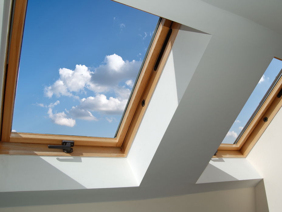Dachgeschoss Fenster aus Holz mit Blick auf den blauen Himmel mit Wolken.