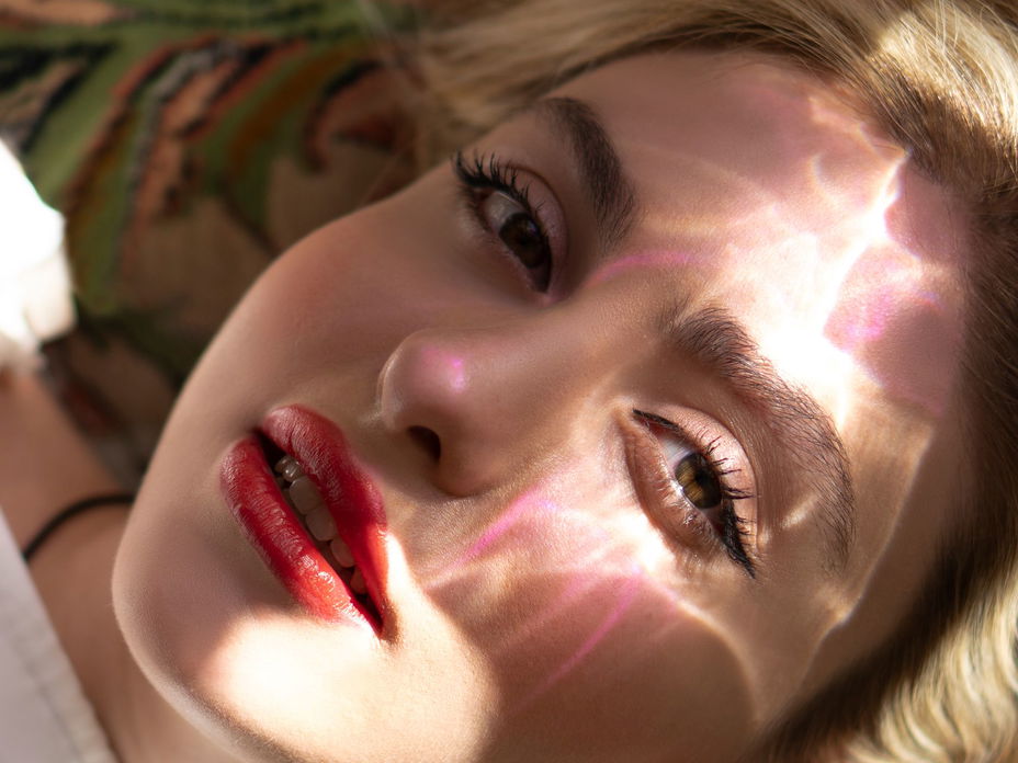 Frau mit glänzendem Lippenstift und Sonne im Gesicht