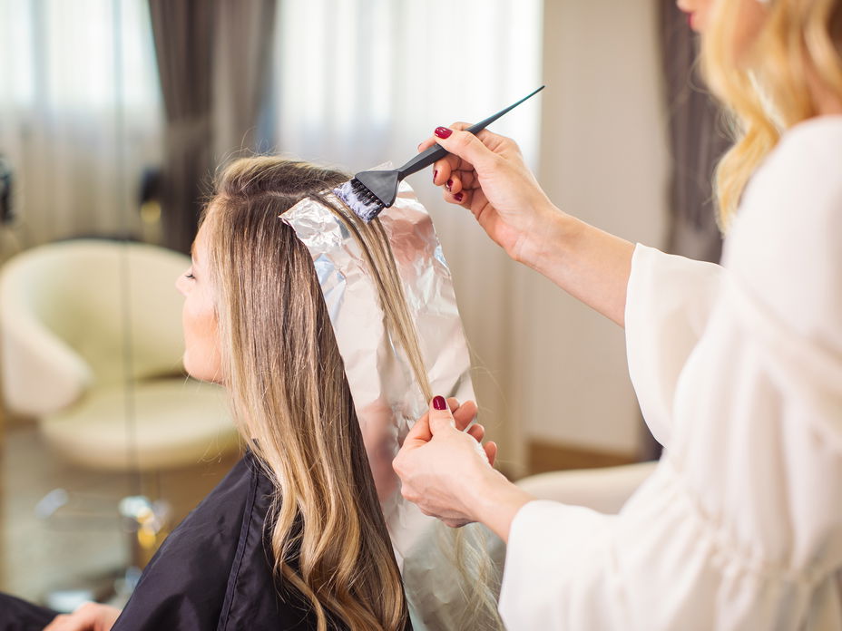 Eine Frau färbt ihre Haare beim Friseur