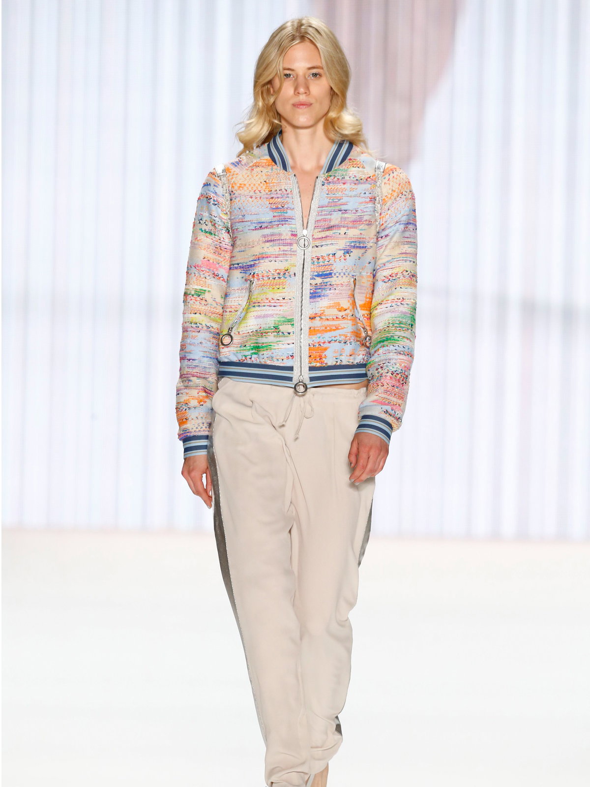 Larissa Marolt auf dem Laufsteg für Riani Spring/Summer 2016 in einer beigefarbenen Hose und einer bunten Jacke.
