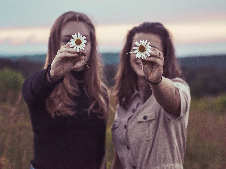 Zwei Frauen halten Blumen vor ihr Gesicht
